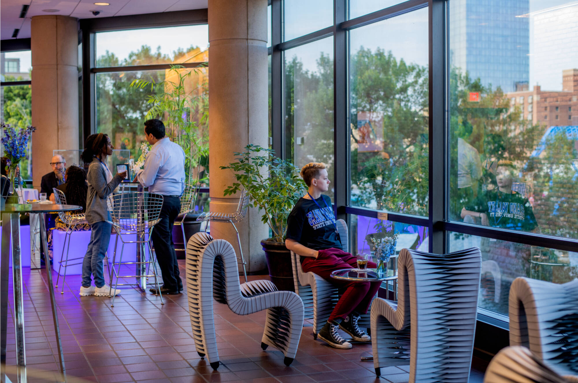 student sits at a table near a window and looks outside